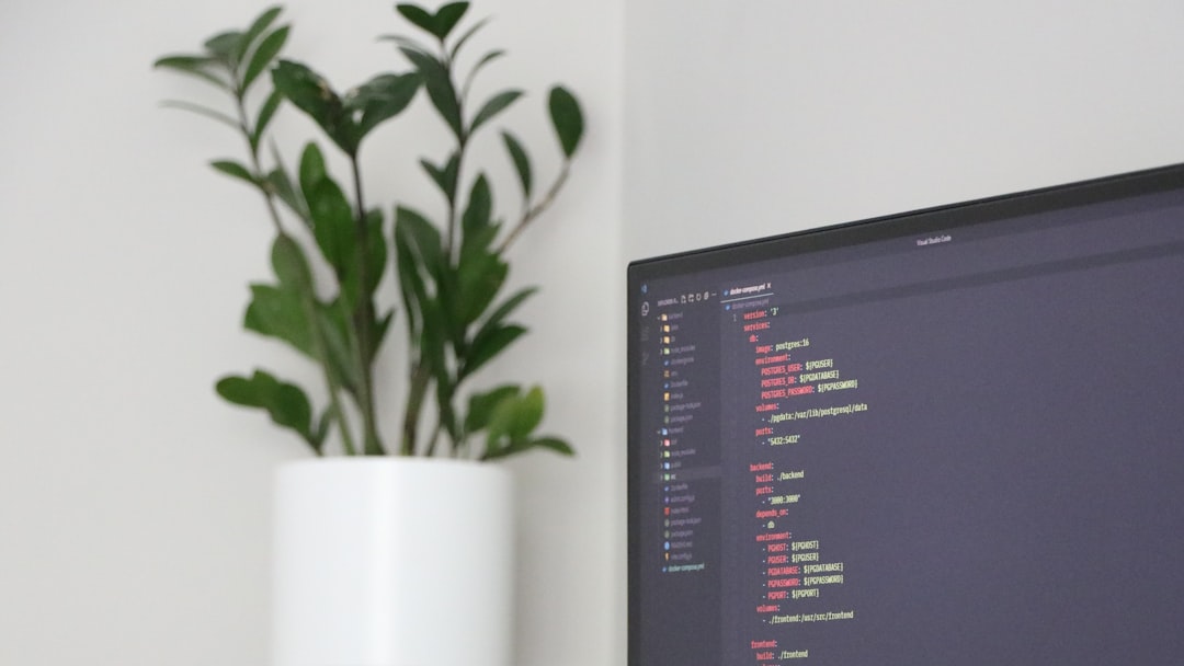 A computer monitor sitting on top of a desk next to a plant
